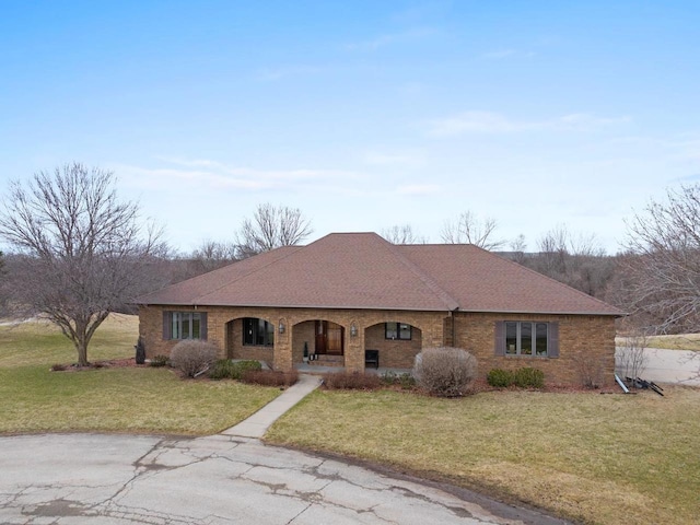 2108 Lawrence Dr, De Pere, WI 54115 - view of front of house with covered porch, a front lawn, a shingled roof, and brick siding