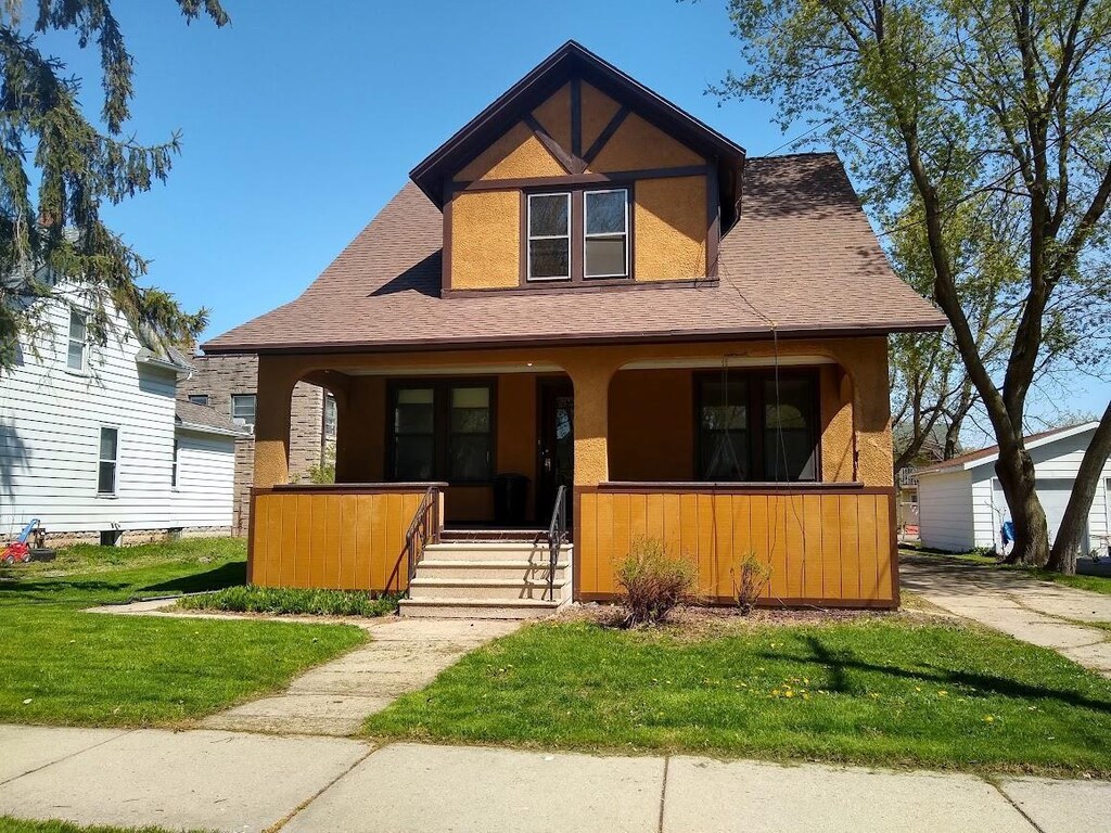 308 E Harrison St, Appleton, WI 54915 - bungalow-style home featuring covered porch, stucco siding, a front lawn, and roof with shingles