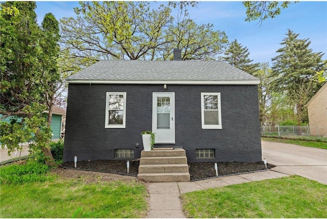 bungalow-style home with entry steps, fence, a chimney, and roof with shingles