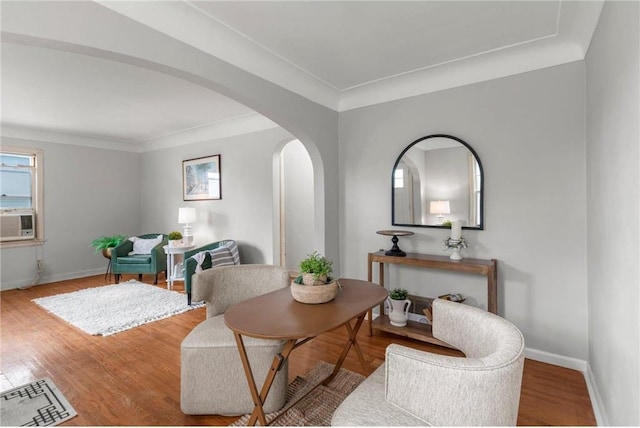 dining space featuring arched walkways, baseboards, wood finished floors, cooling unit, and ornamental molding