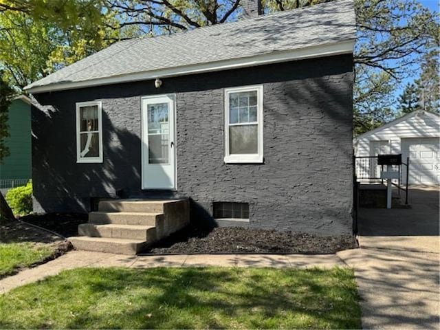view of front of home featuring an outbuilding, a chimney, a shingled roof, and a detached garage