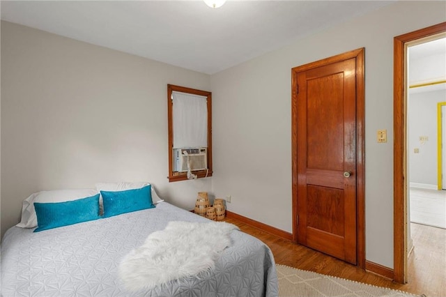 bedroom with wood finished floors, baseboards, and cooling unit