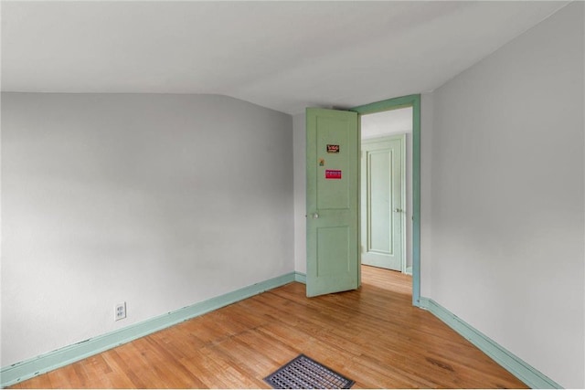 spare room with light wood-style floors, vaulted ceiling, and baseboards