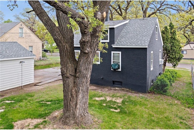 view of side of property featuring roof with shingles and a lawn
