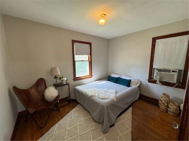 bedroom featuring wood finished floors, cooling unit, and baseboards