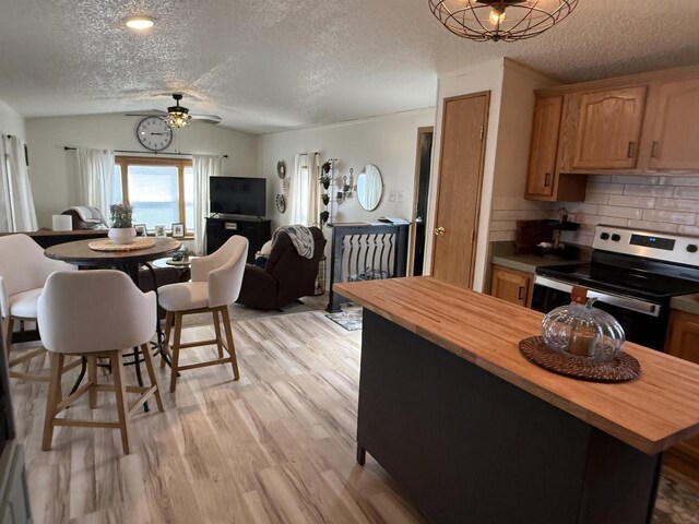 33150 Donna Dr Unit 14, Prairie Du Chien, WI 53821 - kitchen featuring wooden counters, stainless steel range with electric cooktop, a textured ceiling, lofted ceiling, and light wood finished floors