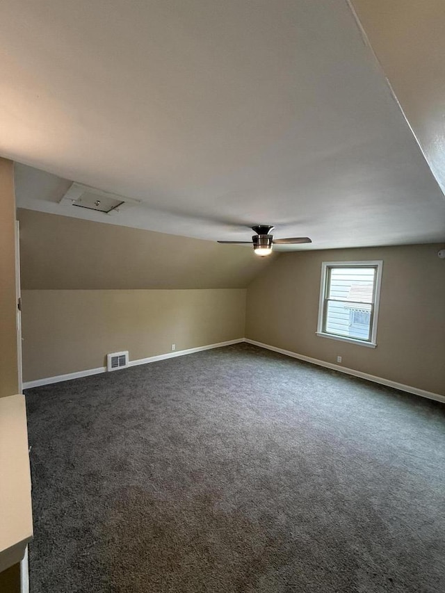 additional living space with dark colored carpet, lofted ceiling, baseboards, and a ceiling fan