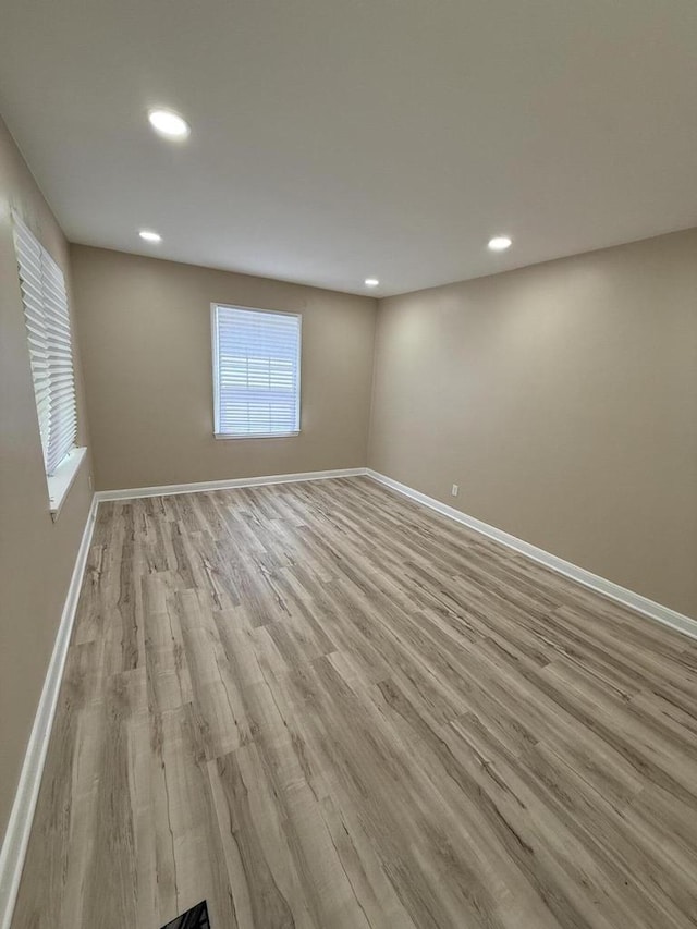 empty room with recessed lighting, light wood-style flooring, and baseboards