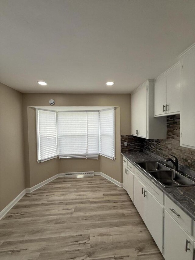 kitchen with a sink, dark countertops, white cabinetry, tasteful backsplash, and recessed lighting
