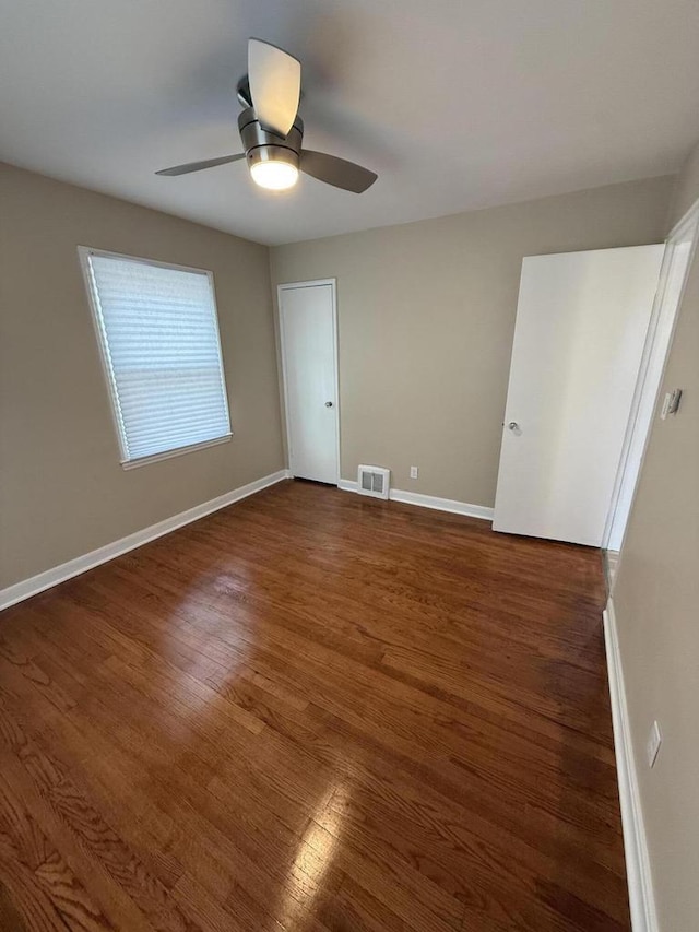 unfurnished bedroom featuring dark wood finished floors, baseboards, and a ceiling fan