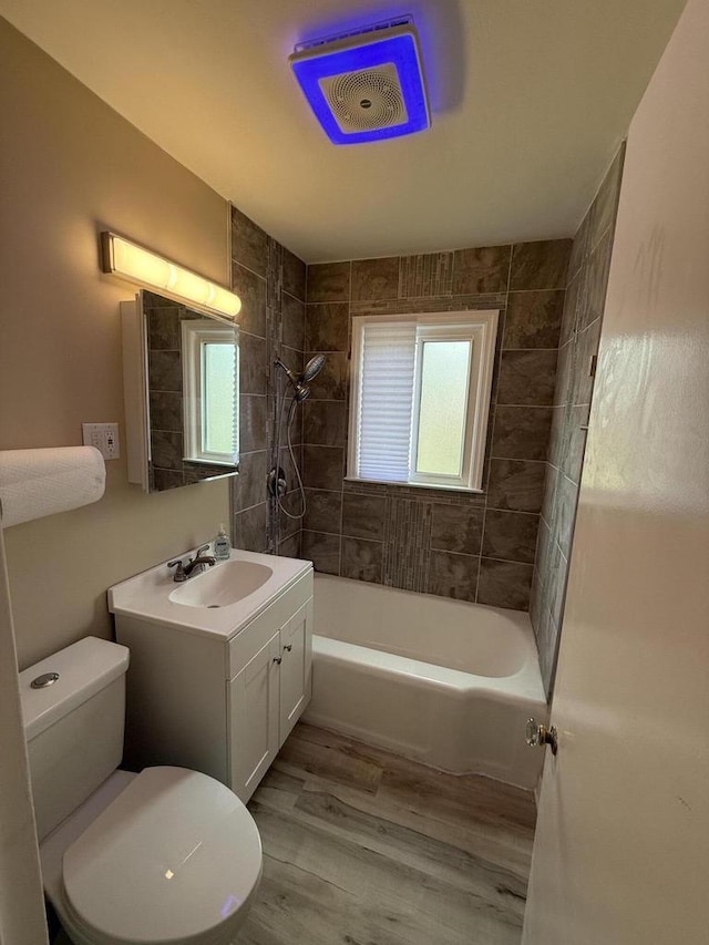 full bath with toilet, vanity,  shower combination, and wood finished floors