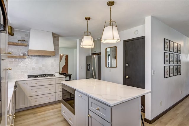 E1924 Kirk Ct, Eau Claire, WI 54701 - kitchen with appliances with stainless steel finishes, custom exhaust hood, light wood-style flooring, decorative backsplash, and a center island