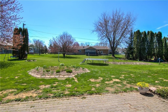 303 W Maple St, Thorp, WI 54771 - view of grassy yard featuring a trampoline