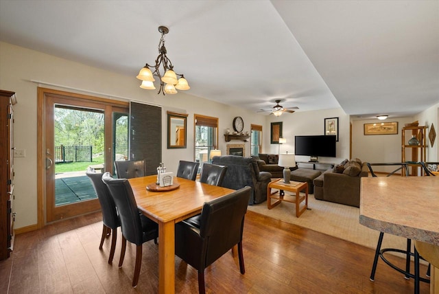 3271 Bay Hill Rd, Port Washington, WI 53074 - dining room featuring a fireplace, dark wood-style flooring, a chandelier, and ceiling fan