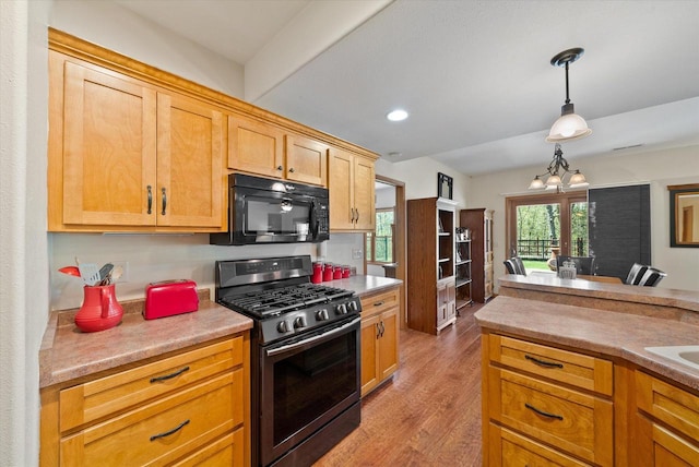 3271 Bay Hill Rd, Port Washington, WI 53074 - kitchen featuring gas range, black microwave, hanging light fixtures, wood finished floors, and light countertops