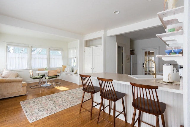 395 Lake St, Green Lake, WI 54941 - kitchen featuring a sink, freestanding refrigerator, a peninsula, wood finished floors, and a breakfast bar area