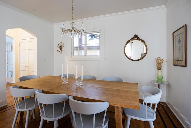 395 Lake St, Green Lake, WI 54941 - dining space featuring a chandelier, dark wood-style flooring, crown molding, arched walkways, and baseboards