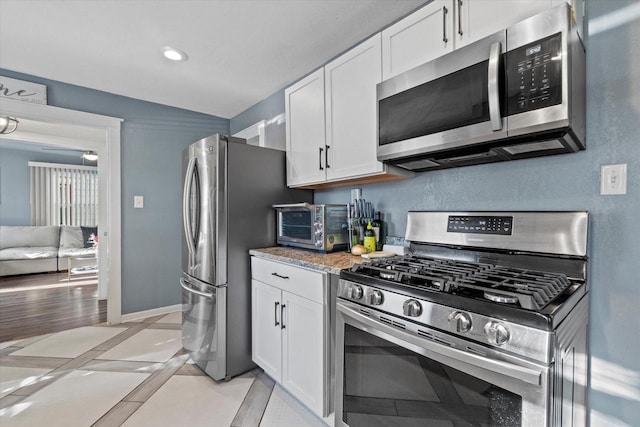 kitchen with stainless steel appliances, white cabinetry, baseboards, and recessed lighting