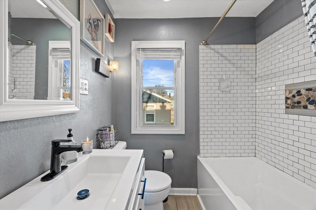 full bathroom with toilet, tub / shower combination, vanity, baseboards, and wood finished floors