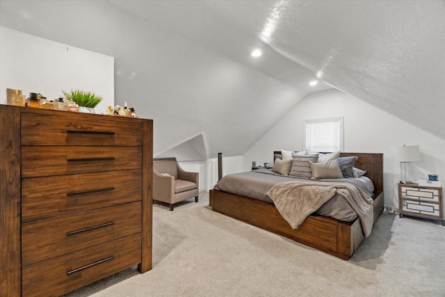 bedroom with light colored carpet, lofted ceiling, and a textured ceiling