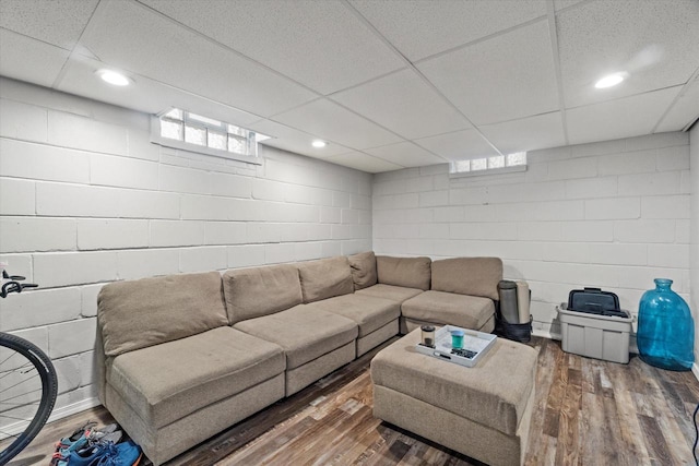 living room with wood finished floors, concrete block wall, and a drop ceiling