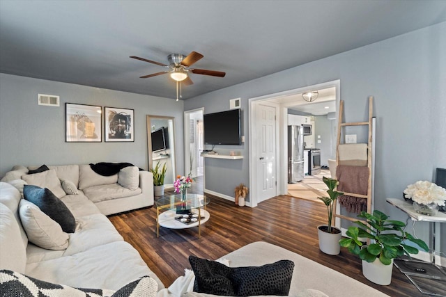 living area with wood finished floors, a ceiling fan, and baseboards