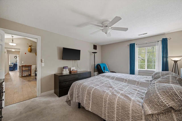 bedroom with carpet floors, a ceiling fan, baseboards, and a textured ceiling