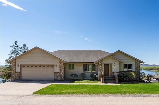ranch-style house featuring an attached garage, driveway, a front yard, brick siding, and a water view