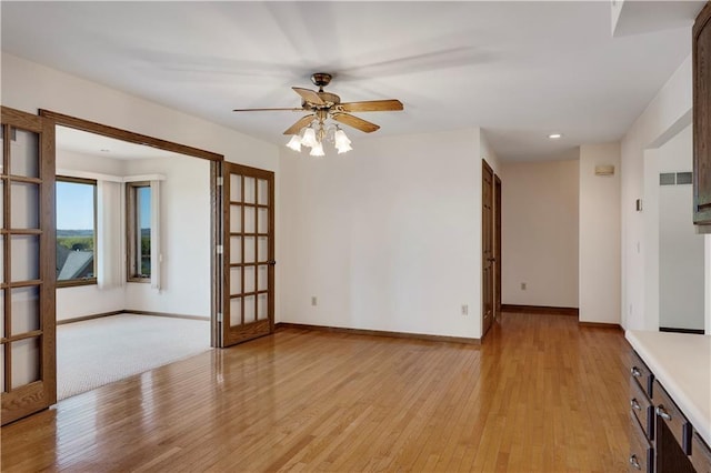 empty room featuring light wood-type flooring, ceiling fan, baseboards, and french doors