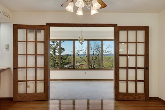 entryway featuring a chandelier, wood finished floors, and baseboards