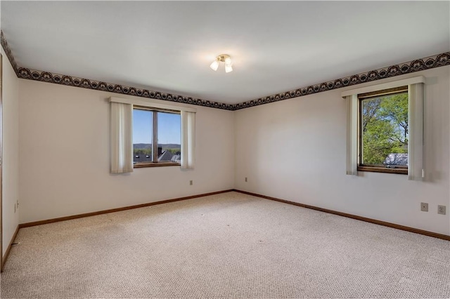 carpeted empty room with healthy amount of natural light and baseboards