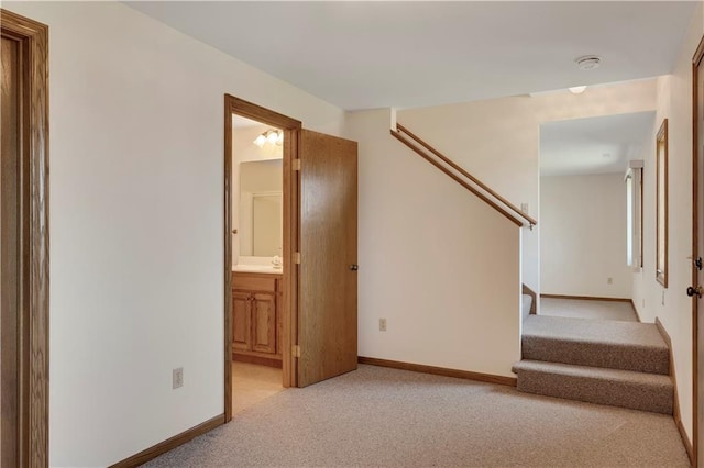 empty room featuring light carpet, stairway, baseboards, and a smoke detector