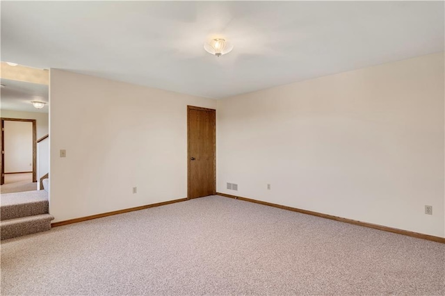 unfurnished room featuring light colored carpet, baseboards, and stairway