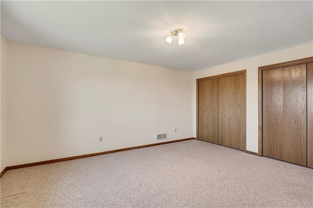 unfurnished bedroom with multiple closets, light colored carpet, and baseboards