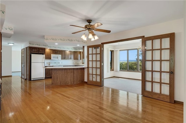 kitchen featuring white appliances, light wood-style flooring, a peninsula, baseboards, and recessed lighting