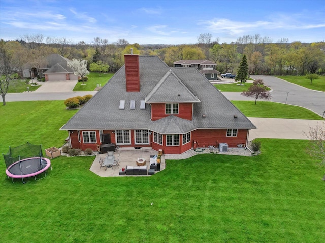 135 Emerald Dr, Mount Pleasant, WI 53406 - rear view of property featuring a patio area, a chimney, a trampoline, a yard, and roof with shingles