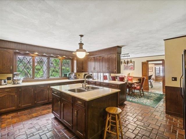 5140 N Kennedy Rd, Milton, WI 53563 - kitchen with a sink, brick floors, light countertops, a center island with sink, and pendant lighting