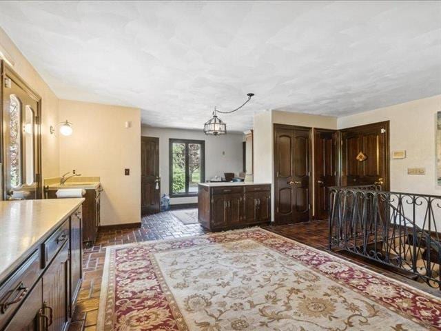 5140 N Kennedy Rd, Milton, WI 53563 - kitchen with dark brown cabinets, a chandelier, a sink, baseboards, and light countertops