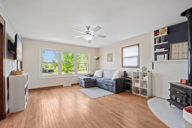841 Legion Dr, Twin Lakes, WI 53181 - living area featuring a wood stove, a ceiling fan, plenty of natural light, and light wood-type flooring