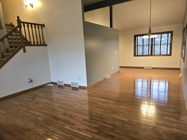 1983 US Highway 2, Florence, WI 54121 - unfurnished living room featuring a chandelier, wood finished floors, stairway, baseboards, and high vaulted ceiling
