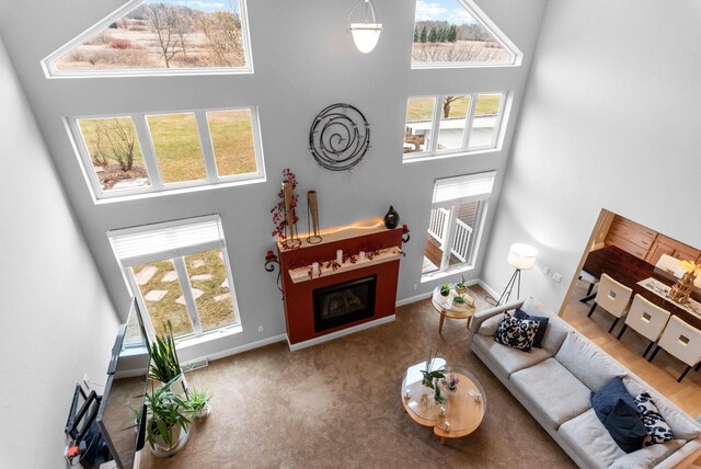 W4344 Carl Dr, Fond Du Lac, WI 54937 - carpeted living area featuring a towering ceiling, a fireplace, plenty of natural light, and baseboards