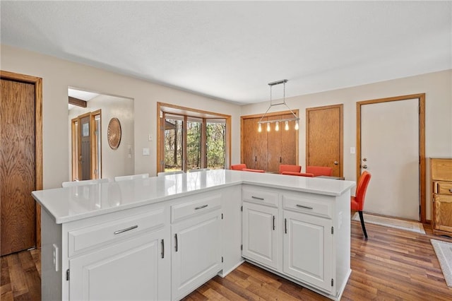 1395 25th St, Houlton, WI 54082 - kitchen with light countertops, wood finished floors, white cabinets, and hanging light fixtures