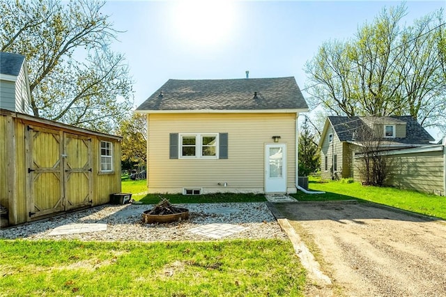 719 Huebsch Blvd, Eau Claire, WI 54701 - rear view of house featuring an outdoor fire pit, an outbuilding, a lawn, and a storage unit