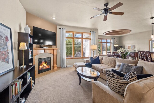 living area with carpet, a ceiling fan, a fireplace, and baseboards