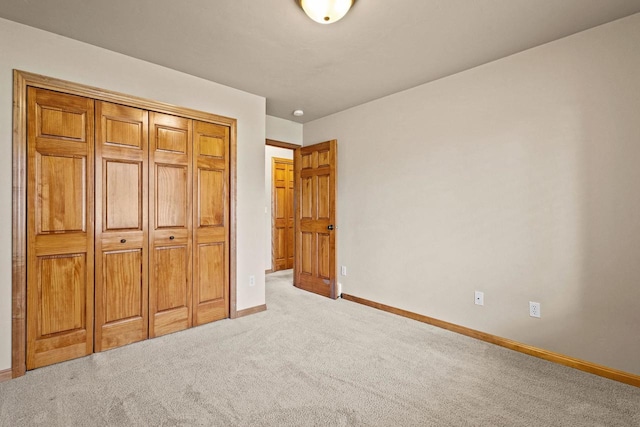 unfurnished bedroom with light carpet, baseboards, and a closet