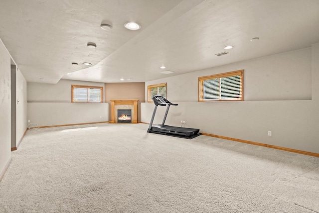 exercise room featuring baseboards, a tile fireplace, carpet, and recessed lighting
