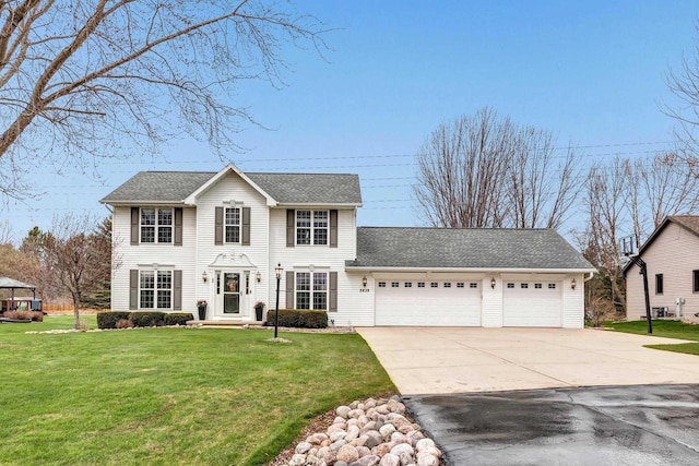 colonial house with an attached garage, driveway, a front lawn, and a shingled roof