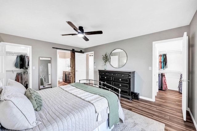 bedroom featuring a spacious closet, a closet, a barn door, and wood finished floors