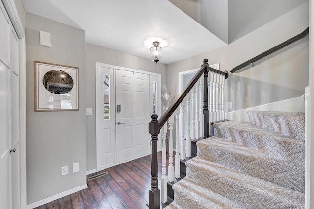 foyer with wood finished floors, baseboards, and stairway