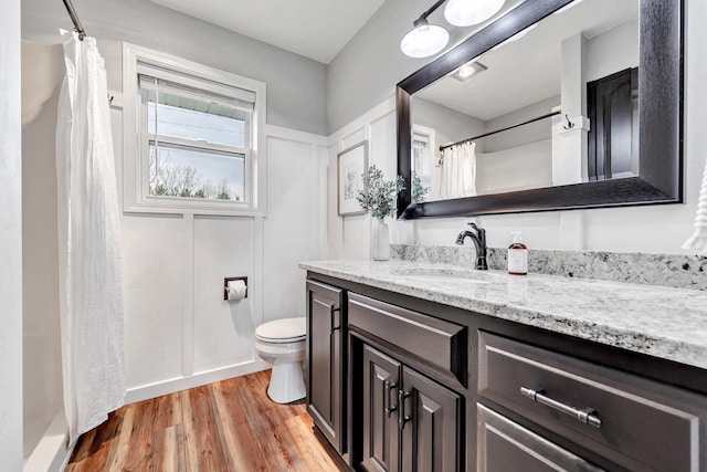 bathroom featuring toilet, wood finished floors, vanity, and a shower with shower curtain